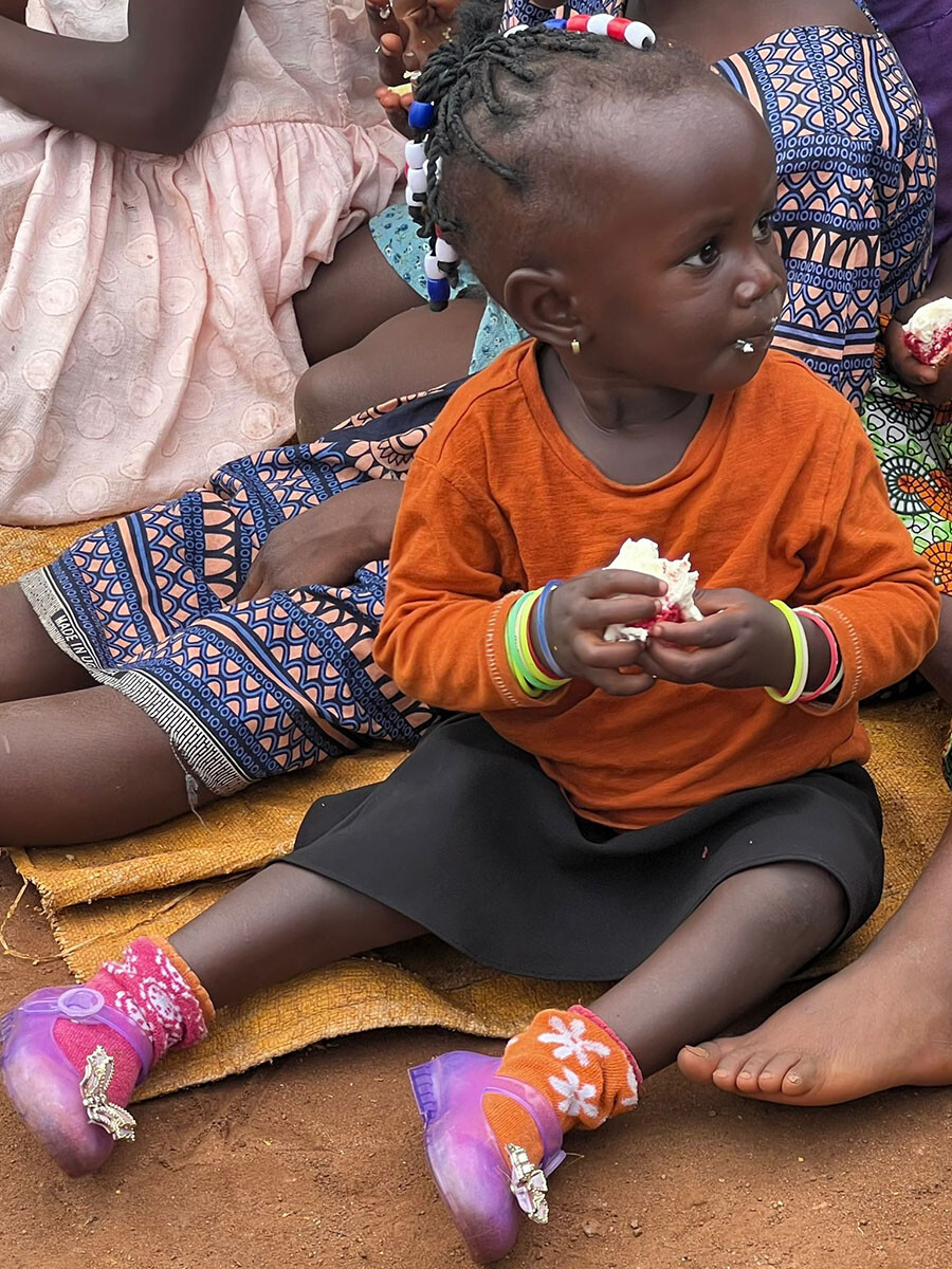 Een peuter van Project Serah buiten op een mat, tussen andere kinderen
